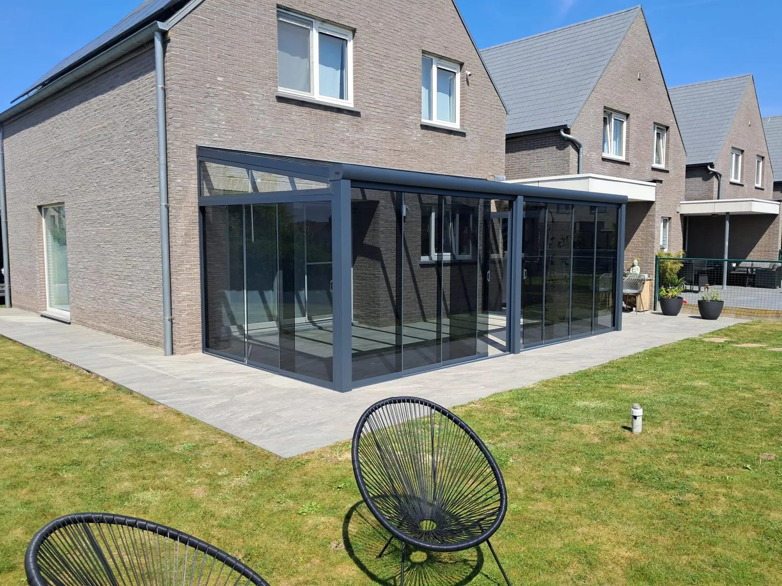 L-vormige veranda met heldere beglazing en glazen dak